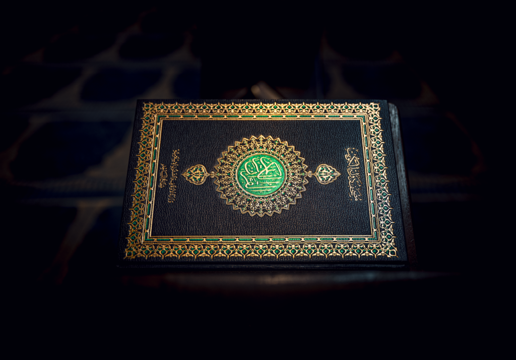 Islamic Holy Quran book with ornate gold detailing, resting on a patterned surface.